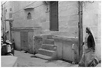 Woman walking in narrow street with blue walls. Jodhpur, Rajasthan, India ( black and white)