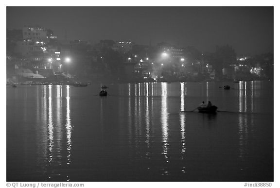 Rowboats and reflected lights on the Ganges River at dusk. Varanasi, Uttar Pradesh, India