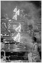 Holy men lifting chandeliers during evening puja. Varanasi, Uttar Pradesh, India (black and white)