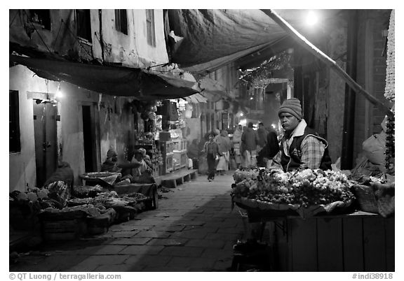 Flower vendor in  narrow old city alley at night. Varanasi, Uttar Pradesh, India