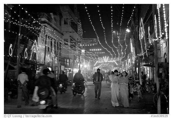 Women walking in street with illuminations. Varanasi, Uttar Pradesh, India (black and white)