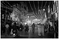 Women walking in street with illuminations. Varanasi, Uttar Pradesh, India (black and white)