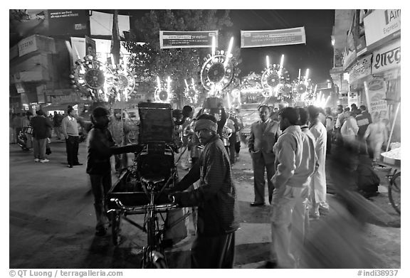 Men pulling generator on bicycle to power lights during wedding procession. Varanasi, Uttar Pradesh, India (black and white)