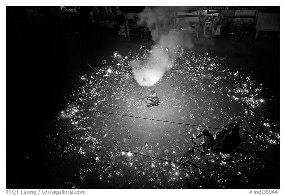 Man firing fireworks in middle of street ahead of wedding procession. Varanasi, Uttar Pradesh, India