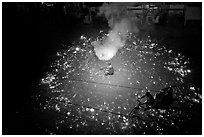 Man firing fireworks in middle of street ahead of wedding procession. Varanasi, Uttar Pradesh, India ( black and white)