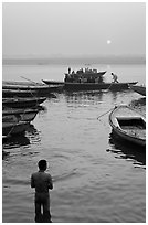 Man standing in Ganga River and boats at sunrise. Varanasi, Uttar Pradesh, India (black and white)