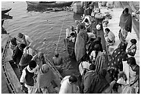 Hindu pilgrims walk out of boat onto Dasaswamedh Ghat. Varanasi, Uttar Pradesh, India (black and white)