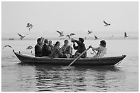 Indian tourists on rawboat surrounded by birds. Varanasi, Uttar Pradesh, India (black and white)