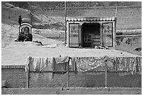 Sadhu sitting next to shrine and laundry. Varanasi, Uttar Pradesh, India ( black and white)