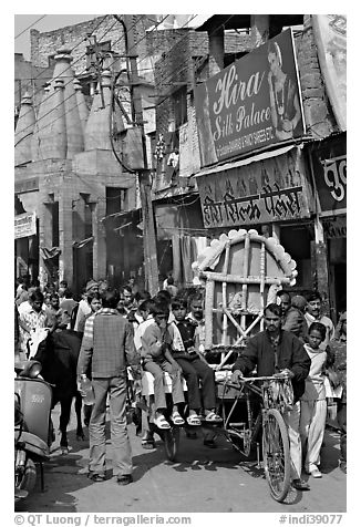 Man moving devotional image and children on rickshaw. Varanasi, Uttar Pradesh, India (black and white)