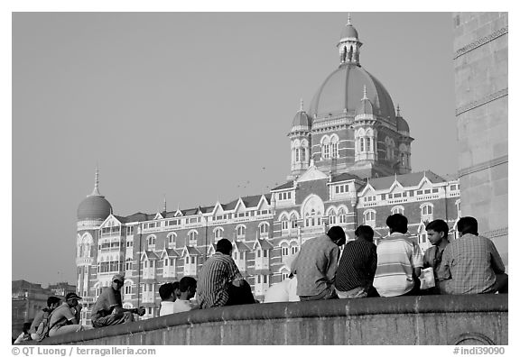 Men sitting in front of Taj Mahal Palace Hotel. Mumbai, Maharashtra, India (black and white)