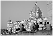 Men sitting in front of Taj Mahal Palace Hotel. Mumbai, Maharashtra, India (black and white)