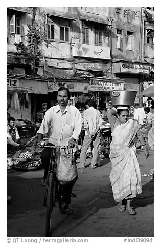 Man riding bike and woman with basket on head, Colaba Market. Mumbai, Maharashtra, India (black and white)