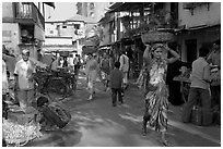 Women carrying  baskets on head in narrow street, Colaba Market. Mumbai, Maharashtra, India ( black and white)