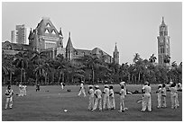 Boys in cricket attire on Oval Maidan, High Court, and Rajabai Tower. Mumbai, Maharashtra, India (black and white)