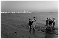 Women walking in water by night, Chowpatty Beach. Mumbai, Maharashtra, India (black and white)