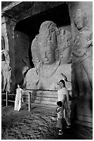 Woman and children standing in front of Mahesh Murti, main  Elephanta cave. Mumbai, Maharashtra, India (black and white)