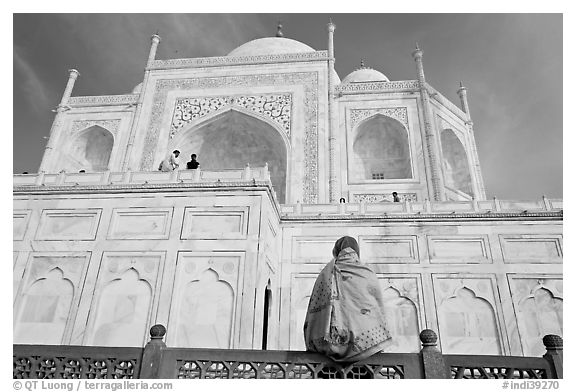 Woman sitting at the base of Taj Mahal looking up. Agra, Uttar Pradesh, India (black and white)