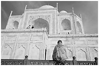 Woman sitting at the base of Taj Mahal looking up. Agra, Uttar Pradesh, India (black and white)