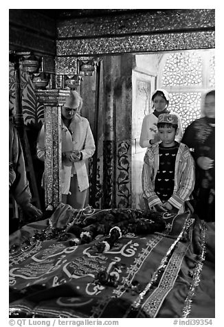 Family making offering on Shaikh Salim Chishti tomb. Fatehpur Sikri, Uttar Pradesh, India (black and white)