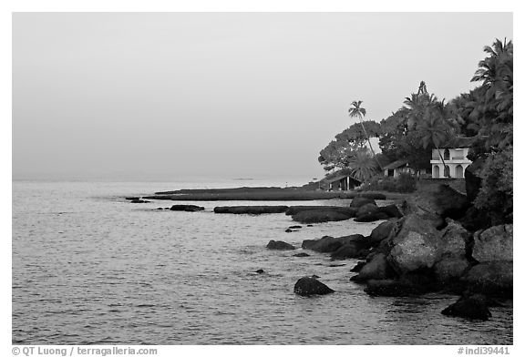 Boulders, beachfront house, and palm trees at sunrise. Goa, India (black and white)