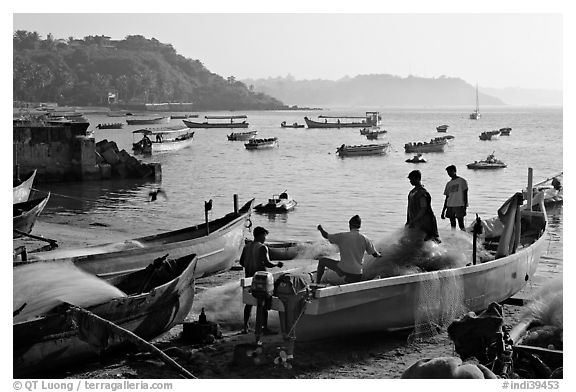 Men repairing net in small fishing boat, early morning, Dona Paula. Goa, India