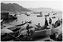 Men repairing net in small fishing boat, early morning, Dona Paula. Goa, India ( black and white)