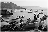 Men repairing net in small fishing boat, early morning, Dona Paula. Goa, India ( black and white)