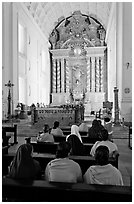Indian women sitting in front of the altar, Basilica of Bom Jesus, Old Goa. Goa, India (black and white)