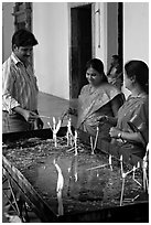 Man and two women burning candles, Basilica of Bom Jesus, Old Goa. Goa, India ( black and white)