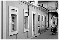 Men on motorbike driving through blue house, Panjim. Goa, India (black and white)