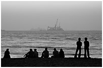 People and  off-shore platforms, Miramar Beach, sunset. Goa, India (black and white)