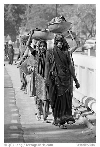 Women walking in line carrying baskets on heads. Khajuraho, Madhya Pradesh, India (black and white)