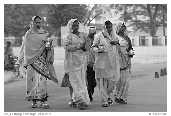 Hindu women walking in street with pots. Khajuraho, Madhya Pradesh, India (black and white)