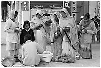 Hindu women purchasing offerings before going to temple. Khajuraho, Madhya Pradesh, India (black and white)