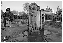 Holy man next to Shiva image. Khajuraho, Madhya Pradesh, India (black and white)