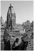 Women worshipping image with temple spire behind. Khajuraho, Madhya Pradesh, India (black and white)