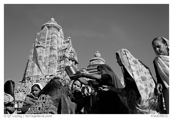 Hindu women making offerings to image with Lakshmana temple behind. Khajuraho, Madhya Pradesh, India (black and white)