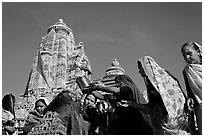 Hindu women making offerings to image with Lakshmana temple behind. Khajuraho, Madhya Pradesh, India ( black and white)