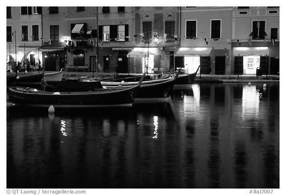 Light of shops reflected in harbor at dusk, Portofino. Liguria, Italy