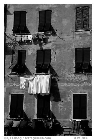 Typical terra cotta facade with hanging laundry and green shutters, Vernazza. Cinque Terre, Liguria, Italy (black and white)