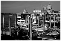 Water taxi driver cleaning out his boat in the morning, Santa Maria della Salute in the background. Venice, Veneto, Italy (black and white)
