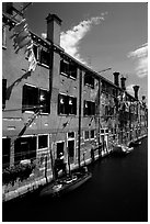 Resident stepping from his doorway to his boat,  Castello. Venice, Veneto, Italy (black and white)