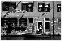 Resident stepping from his boat to his house,  Castello. Venice, Veneto, Italy ( black and white)
