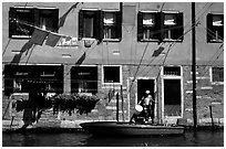 Resident stepping from his boat to his house,  Castello. Venice, Veneto, Italy (black and white)