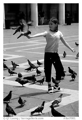 Girl playing with the pigeons, Piazzetta San Marco (Square Saint Mark), mid-day. Venice, Veneto, Italy (black and white)