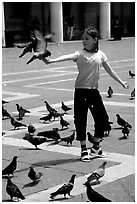 Girl playing with the pigeons, Piazzetta San Marco (Square Saint Mark), mid-day. Venice, Veneto, Italy (black and white)