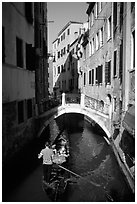 Gondola tour in a picturesque canal with bridge. Venice, Veneto, Italy (black and white)