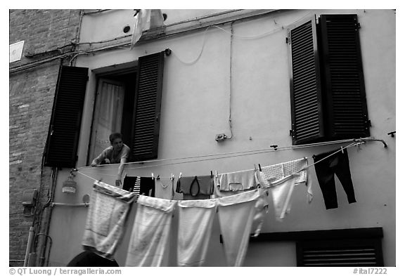 Woman hanging laundry. Siena, Tuscany, Italy