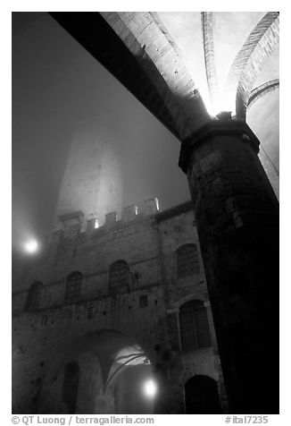 Medieval towers above Piazza del Duomo, foggy night. San Gimignano, Tuscany, Italy